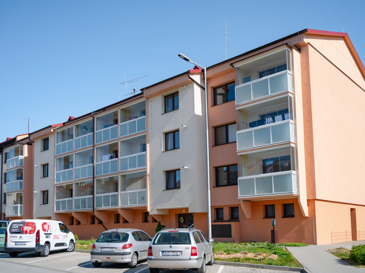 Diagonální pohled na bytový dům osazený novými betonovými předsazenými lodžiemi